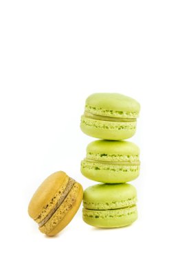 Beyaz arka planda, maccarone şekerli tatlı bir kahverengi macaron yakınındaki izole yığılmış yeşil pasta macaron