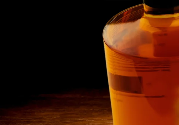 Botella de whisky sobre fondo de mesa de madera oscura — Foto de Stock