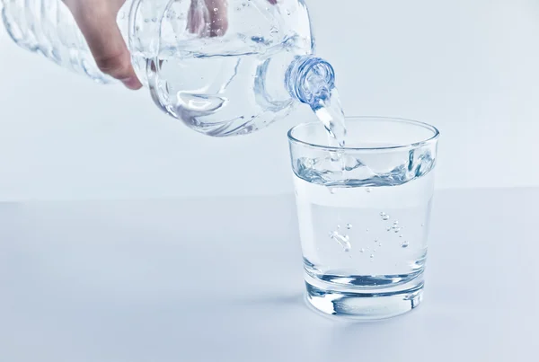 Vullen van een glas met water door middel van fles, voeding en gezondheidszorg concept — Stockfoto