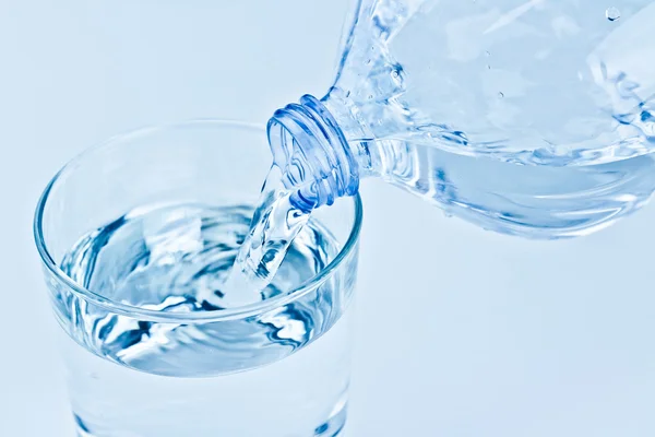 Remplir un verre avec de l'eau à travers la bouteille, la nutrition et le concept de soins de santé — Photo