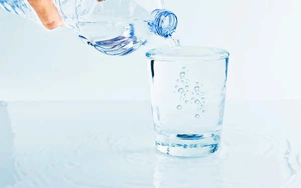 Vullen van een glas met water door middel van fles, voeding en gezondheidszorg concept — Stockfoto