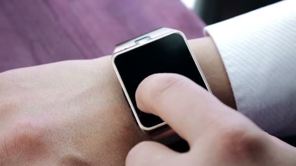 homme utilisant l'application smartwatch avec son doigt sur la table en bois 