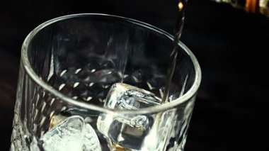 ahşap masa üzerinde buz küpleriyle bardakta viski dökme barmen Close-Up