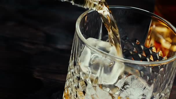 Nahaufnahme von Barmann, der Whiskey mit Eiswürfeln auf Holztisch gießt — Stockvideo