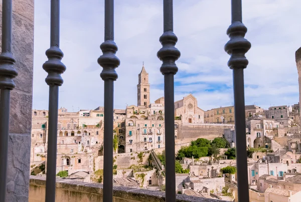 Vista panorámica de las piedras típicas (Sassi di Matera) y la iglesia de Matera vista a través de la puerta bajo el cielo azul —  Fotos de Stock