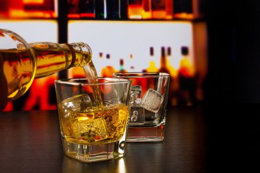 barman pouring whiskey in front of whiskey glass and bottles clipart