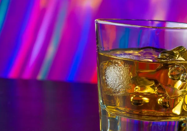 Стакан виски со льдом на барном столе в теплой атмосфере — стоковое фото