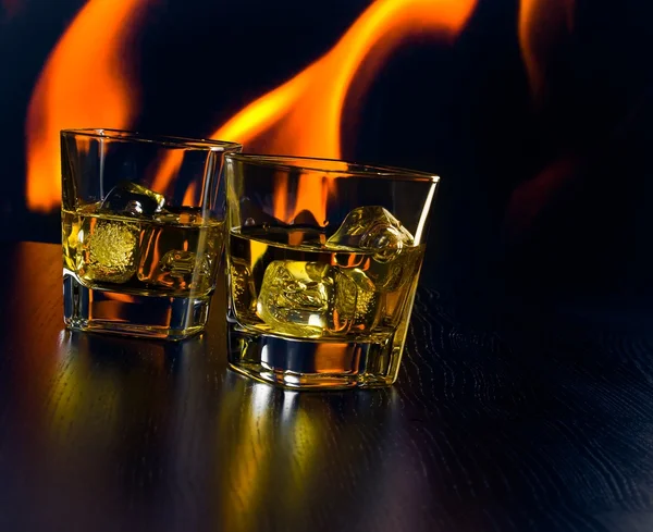 Szklanki whisky z kostkami lodu przed płomień — Zdjęcie stockowe