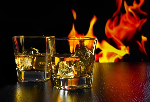 Glasses of whiskey with ice cubes in front of the flame — Stock Photo, Image