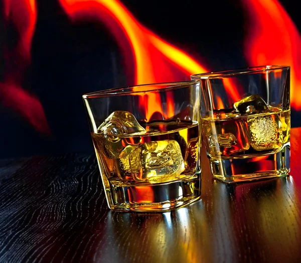 Dwie szklanki whisky z kostkami lodu przed płomień — Zdjęcie stockowe