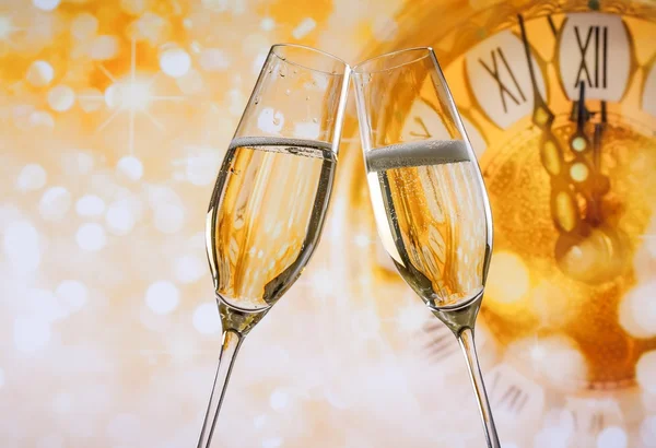 Año Nuevo o Navidad a medianoche con flautas de champán hacen vítores, bokeh dorado y reloj — Foto de Stock