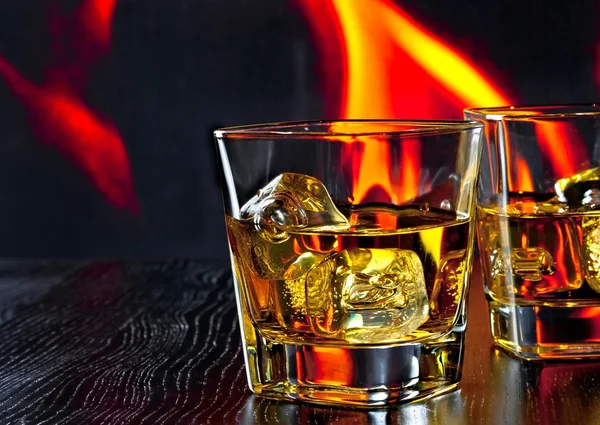 iki kadeh viski ateşin önünde buz küpleri ile