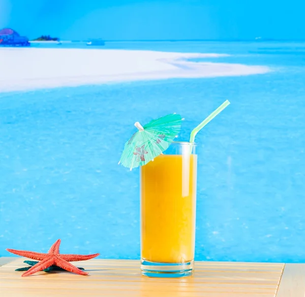 Kieliszek soku pomarańczowego na plaży — Zdjęcie stockowe