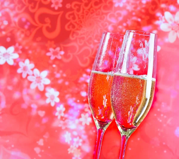 Champagne flutes with golden bubbles on red vintage background — Stock Photo, Image