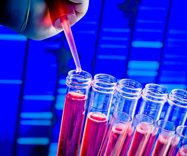 Primo piano delle provette con pipetta su liquido rosso su fondo sequenza DNA astratto — Foto Stock