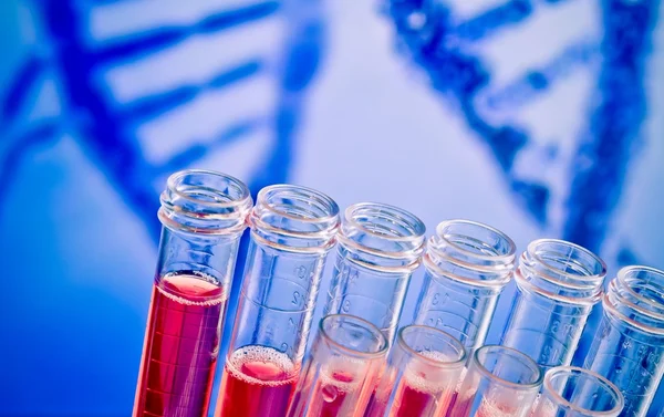 Primo piano delle provette con liquido rosso su fondo di DNA astratto — Foto Stock