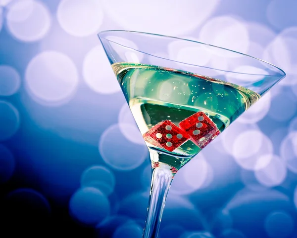 Dadi rossi nel bicchiere da cocktail su bokeh azzurro — Foto Stock