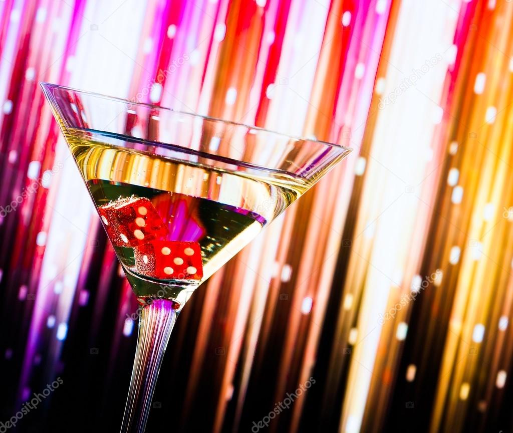 red dice in the cocktail glass on colorful gradient