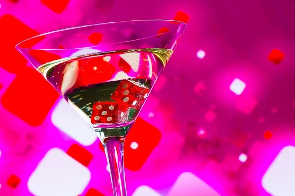 Rode dobbelstenen in de cocktailglas op wazig roze achtergrond — Stockfoto