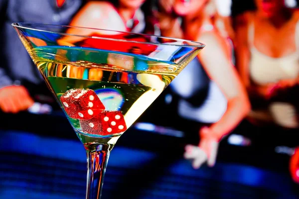 Red dice in the cocktail glass in front of gambling table — Stock Photo, Image