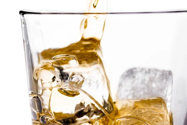 Början hälla scotch whisky i glas med isbitar på vit — Stockfoto