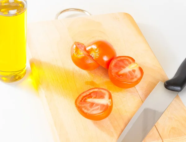 Arriba de la vista de tomates cherry frescos y maduros en una tabla de cortar vieja. Frasco de aceite de oliva en el fondo —  Fotos de Stock