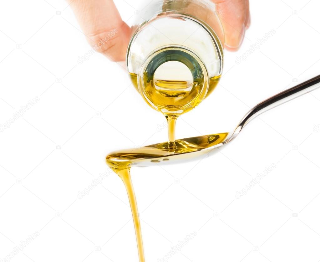 Bottle of extra virgin olive oil pouring over a spoon isolated on white background