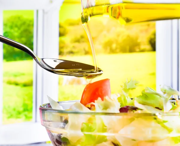 Extra virgin olive oil bottle pouring in the Italian fresh salad — Stock Photo, Image