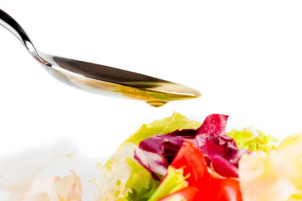 Sked med olivolja och släppa på italiensk färsk sallad på vit — Stockfoto
