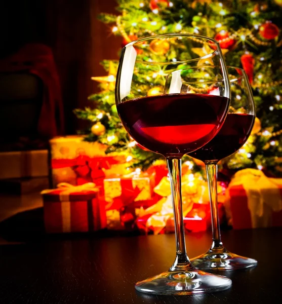 Two red wine glasses against christmas tree background — Stock Photo, Image