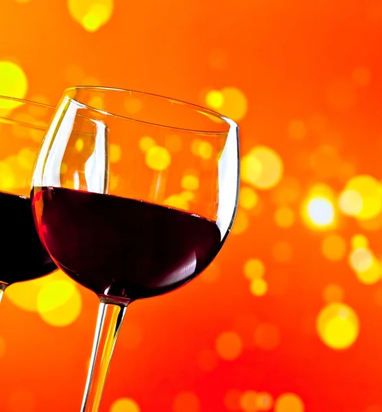 Two red wine glasses against golden bokeh lights background — Stock Photo, Image