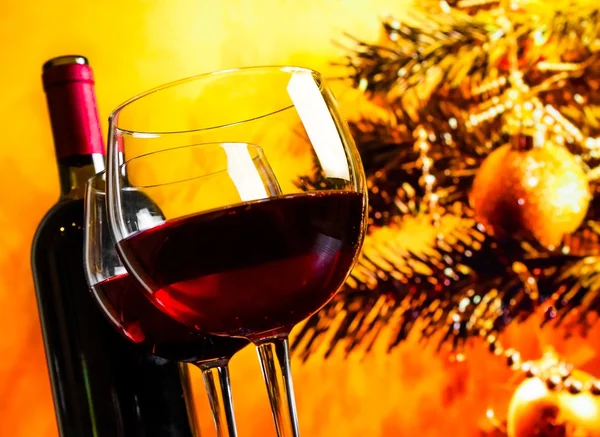 Iki kırmızı şarap kadehi şişe Noel ağacı arka plan yakınındaki — Stok fotoğraf