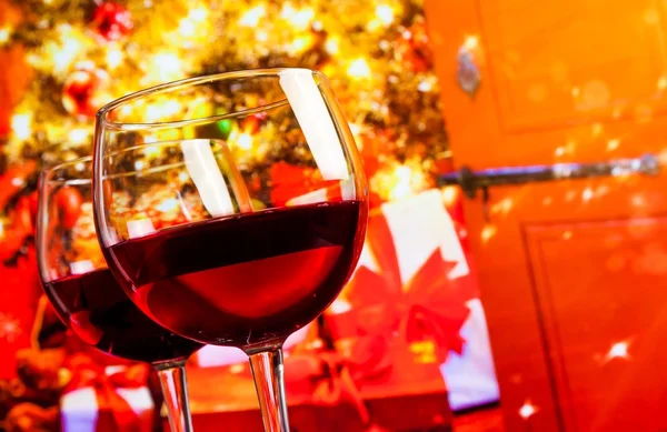 Detail of two red wine glasses against christmas tree background — Stock Photo, Image