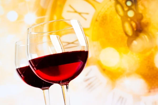 Due bicchieri di vino rosso contro sfondo orologio d'oro — Foto Stock