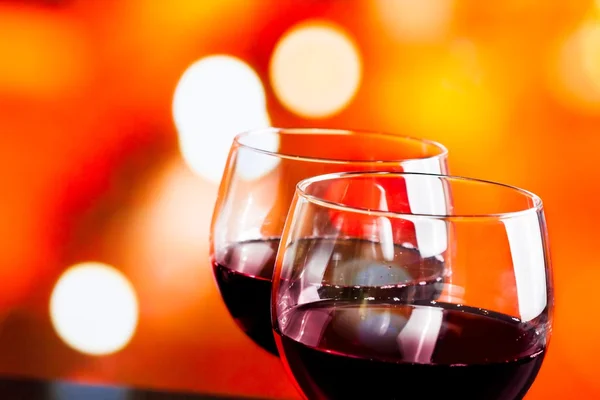 Red wine glasses against colorful unfocused lights background — Stock Photo, Image