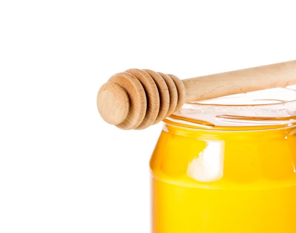 Closeup of opened honey jar on white background with wooden honey dipper — Stock Photo, Image