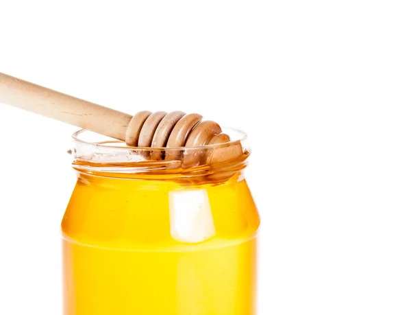 Closeup of opened honey jar on white background with wood honey dipper inside — Stok Foto