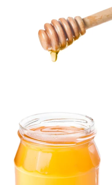 Honey jar på vit bakgrund med trä honung skopa på toppen och droppe honung — Stockfoto