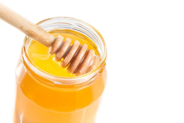 Top of view of opened honey jar on white background with wooden honey dipper inside — Stock Photo, Image