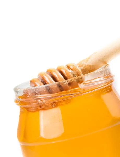 Closeup of opened honey jar on white background with wooden honey dipper inside — Stock Photo, Image