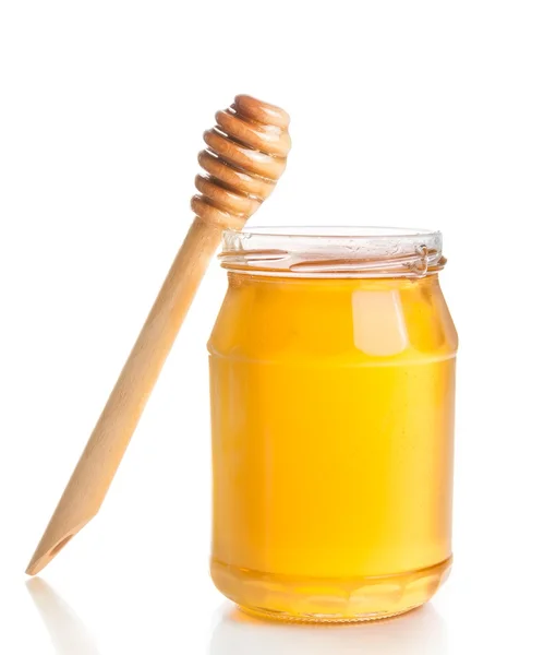 Opened honey jar on white background near wooden honey dipper — Stock Photo, Image