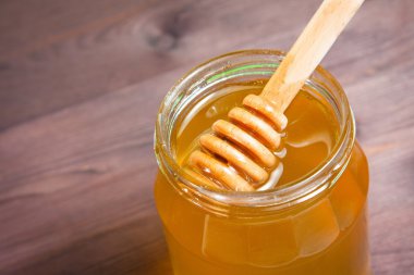 üstte ahşap kepçe ile ahşap masa üzerinde bal kavanozu