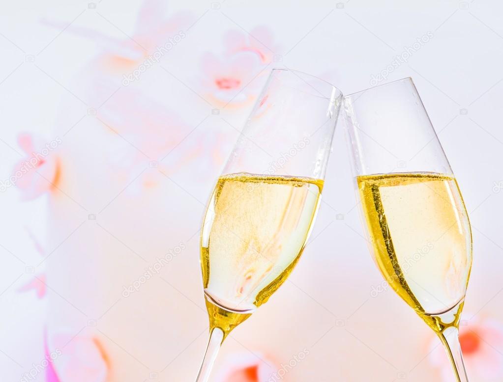 champagne flutes with golden bubbles on wedding cake background