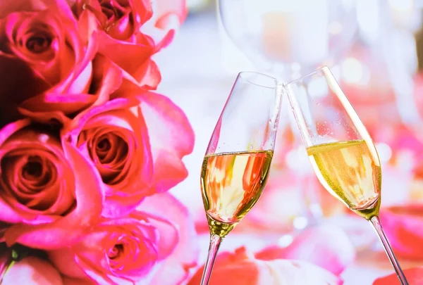 Champagne flutes with golden bubbles on wedding roses flowers background — Stock Photo, Image