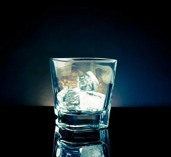 Szklane puste whisky z lodem i jasny odcień niebieski disco na czarnym tle — Zdjęcie stockowe