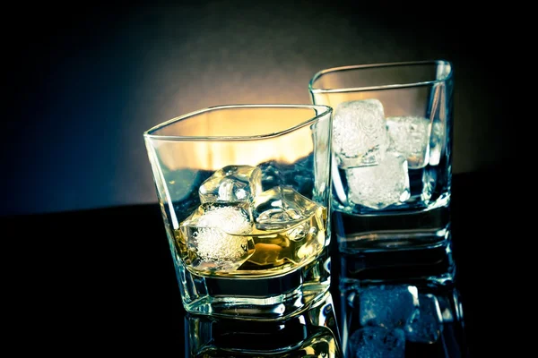 Whiskey glasses with ice and light tint blue disco on black background — Stock Photo, Image