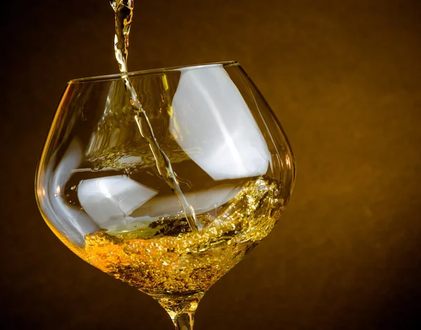 Versando vino bianco in un bicchiere con spazio per il testo, atmosfera calda — Foto Stock