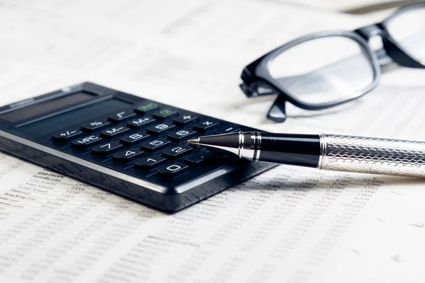 Caneta fonte de negócios, calculadora e óculos no gráfico financeiro — Fotografia de Stock