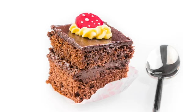 Deliciosa rebanada de pastel de chocolate con crema y azúcar en la parte superior cerca de una cuchara —  Fotos de Stock