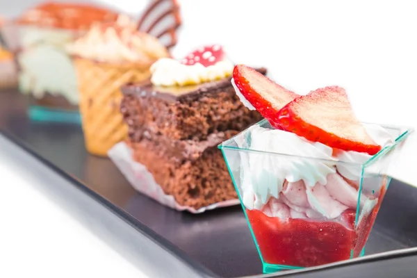 Delicioso pastel de fresa con crema delante de pequeños pasteles de chocolate y café —  Fotos de Stock
